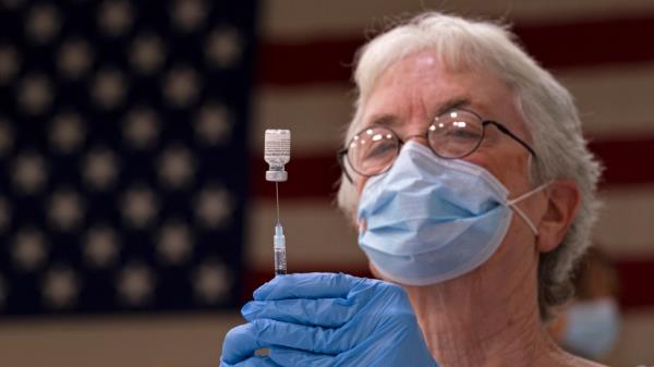 Pam Hetherly fills a syringe with COVID-19 vaccine at a clinic at the Augusta Armory, Dec. 21, 2021, in Augusta, Maine. More than a year after the vaccine was rolled out, new cases of COVID-19 in the U.S. have soared to the highest level on record at over 265,000 per day on average, a surge driven largely by the highly co<em></em>ntagious omicron variant. (AP Photo/Robert F. Bukaty, File)