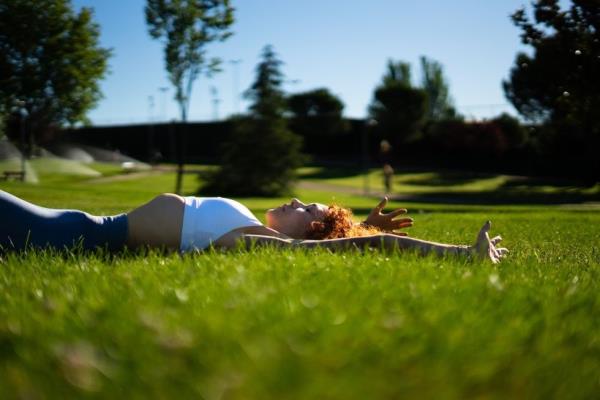 A woman lying in the grass while doing exercisesq